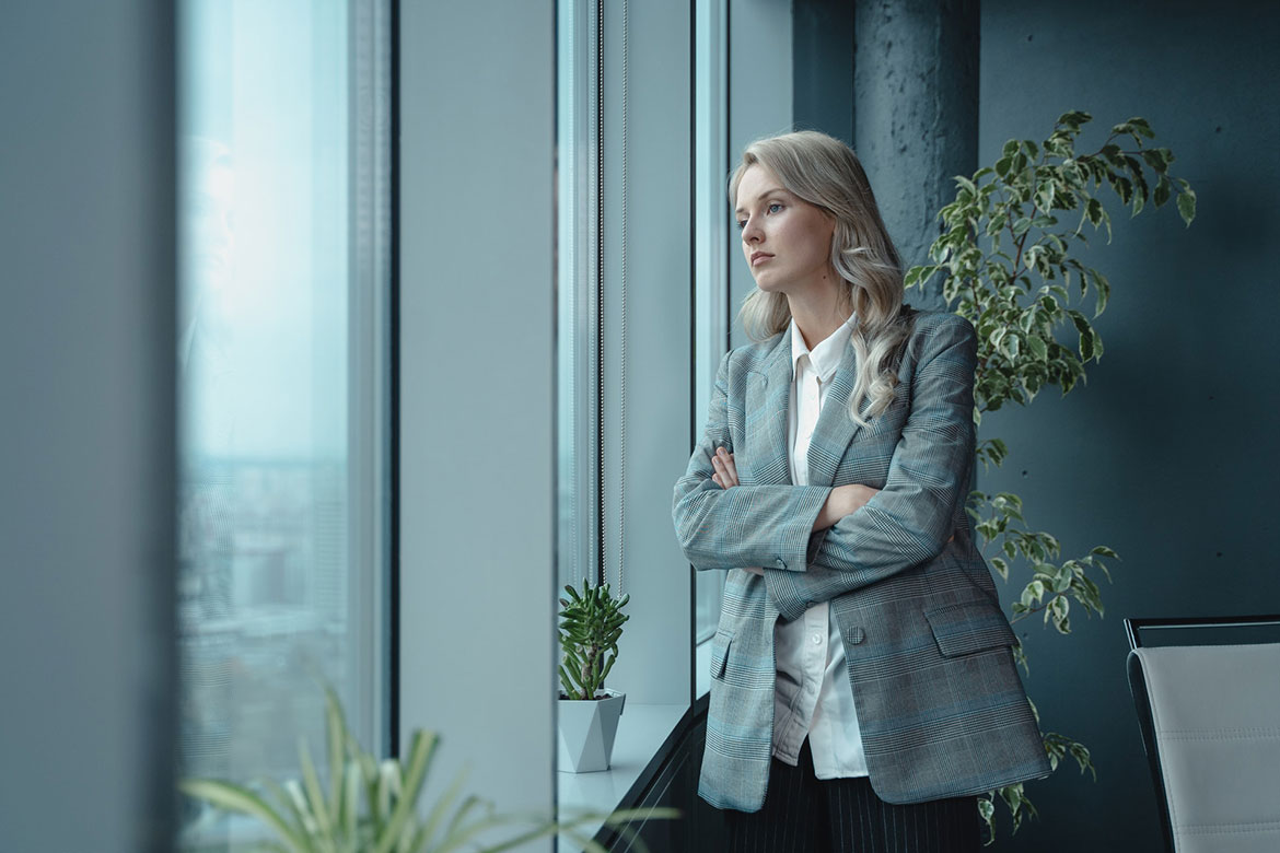 Female CEO in gray blazer looking out of office
