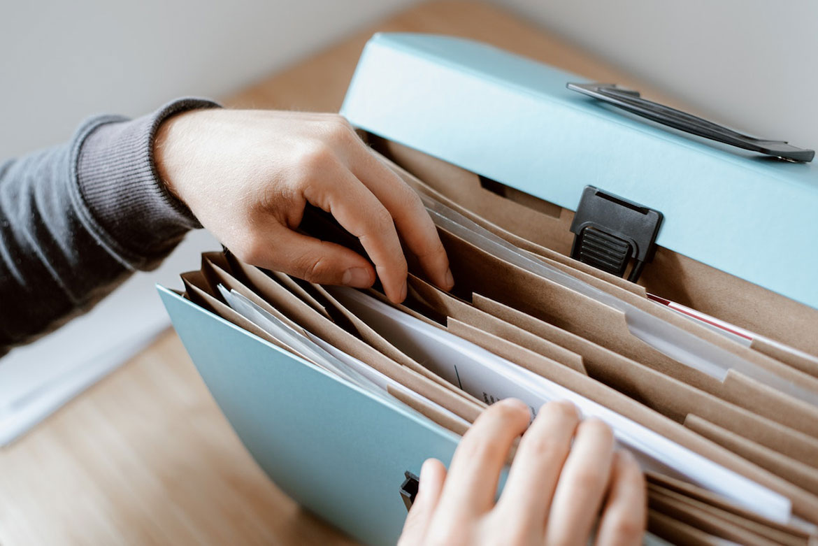 Image of hands going through full accordion file folder full of paperwork