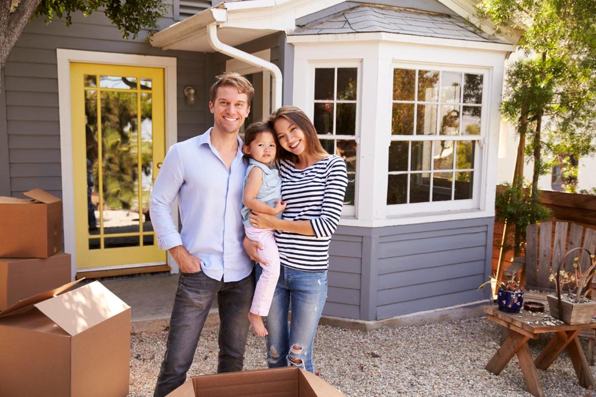 Portrait of an excited family standing outside a new home.