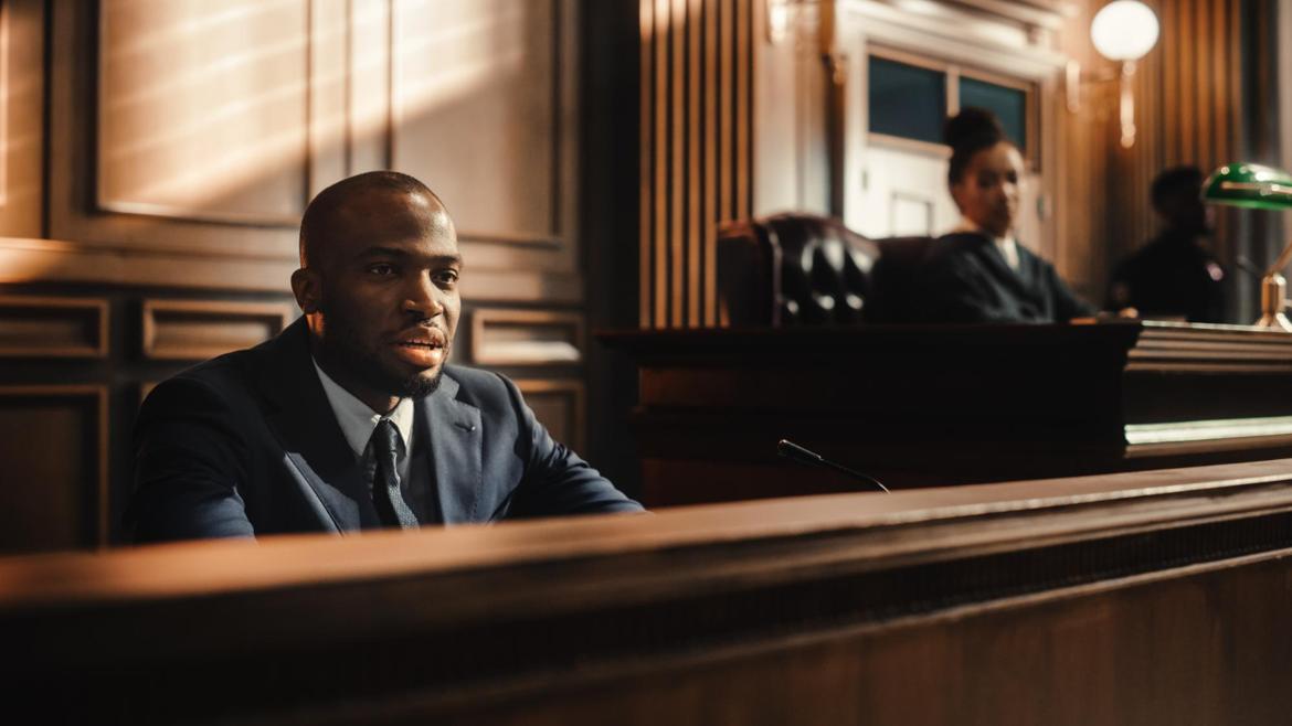 Male witness giving testimony to a judge in a court of law.