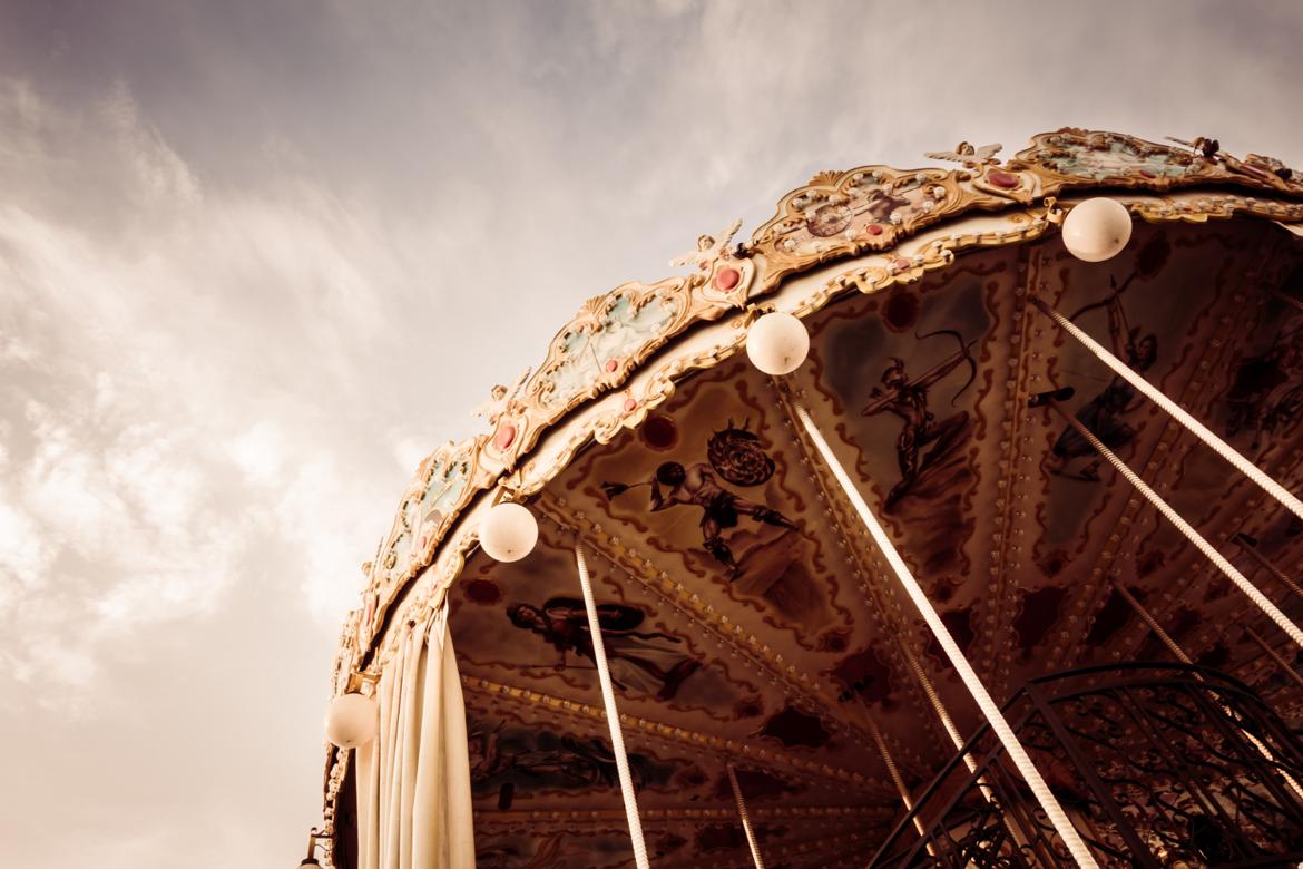 Low-angle view of a carousel ride against a cloudy sky