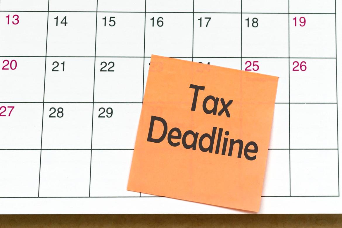 The words “tax deadline” written on an orange sticky note stuck to a calendar.