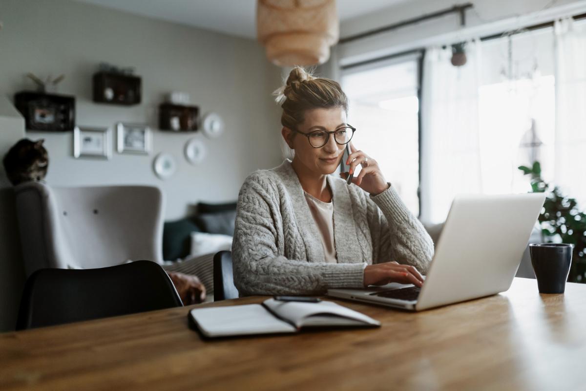 Businesswoman working on laptop computer sitting at home and managing her business via home office