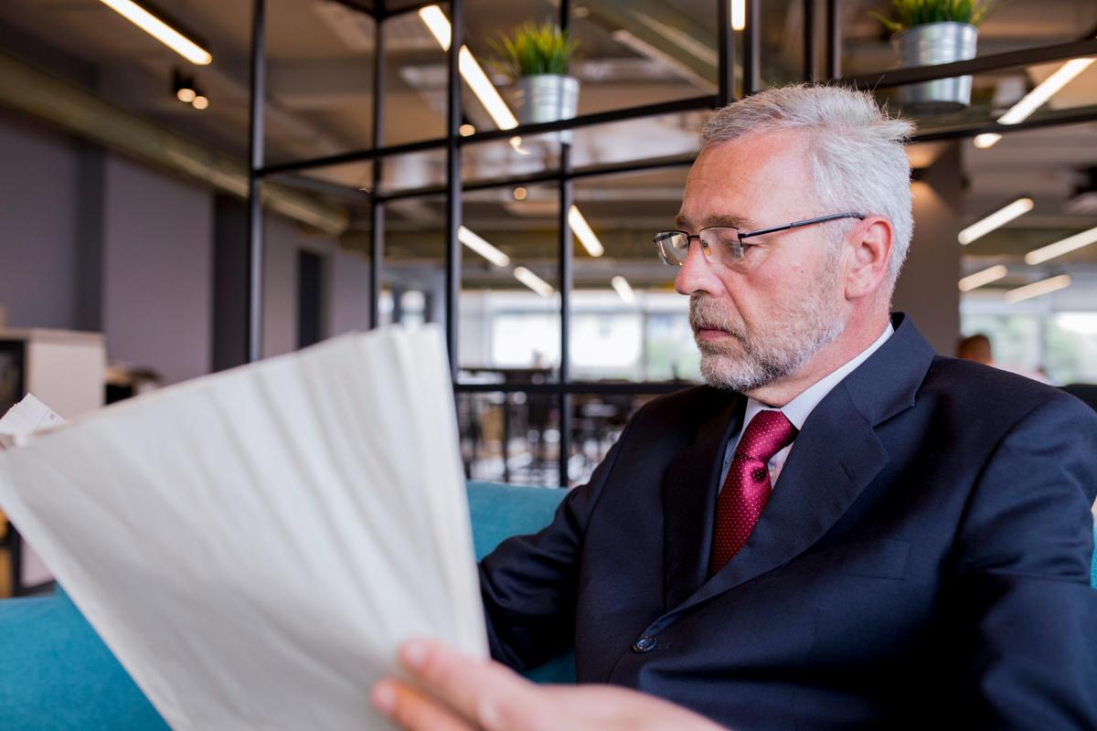Older man in a business suit examining paperwork