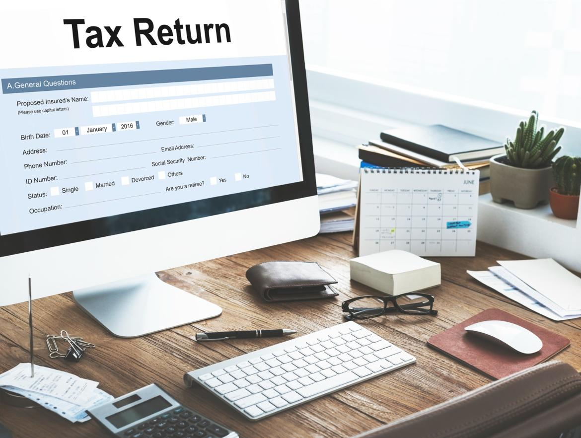 Work desk with business accessories and a computer monitor displaying a tax return form.