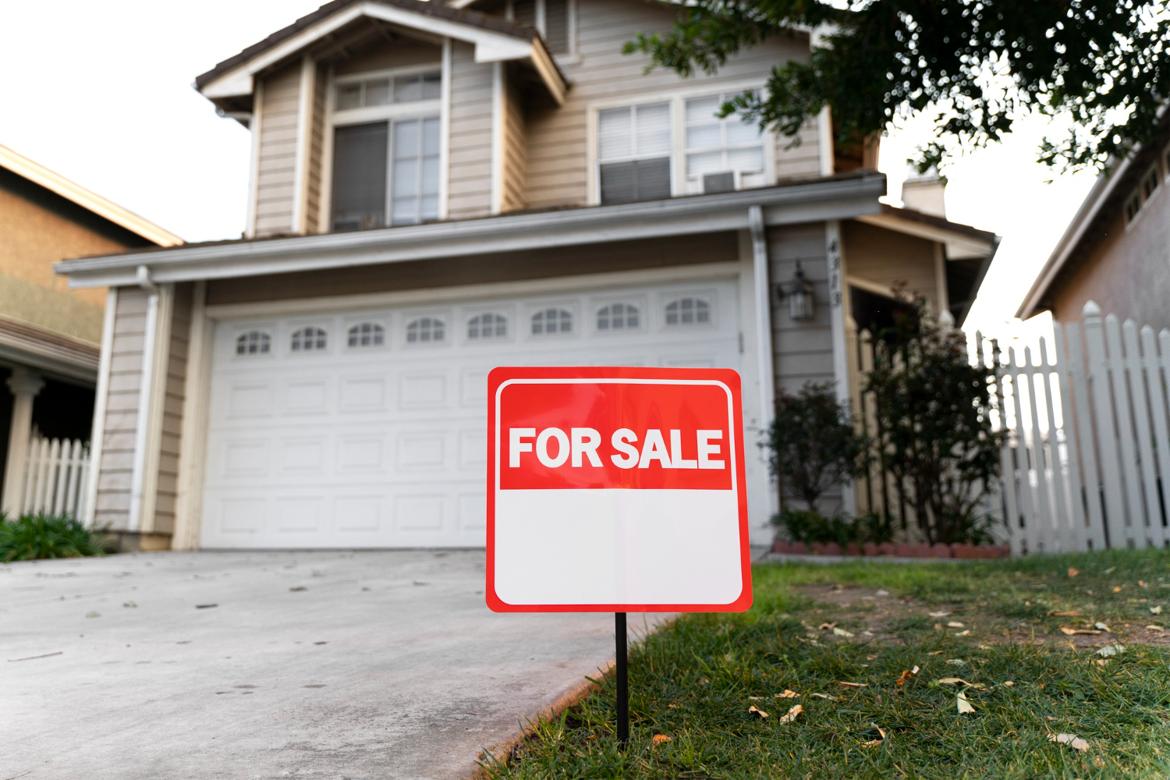 House with a For Sale sign in the front yard