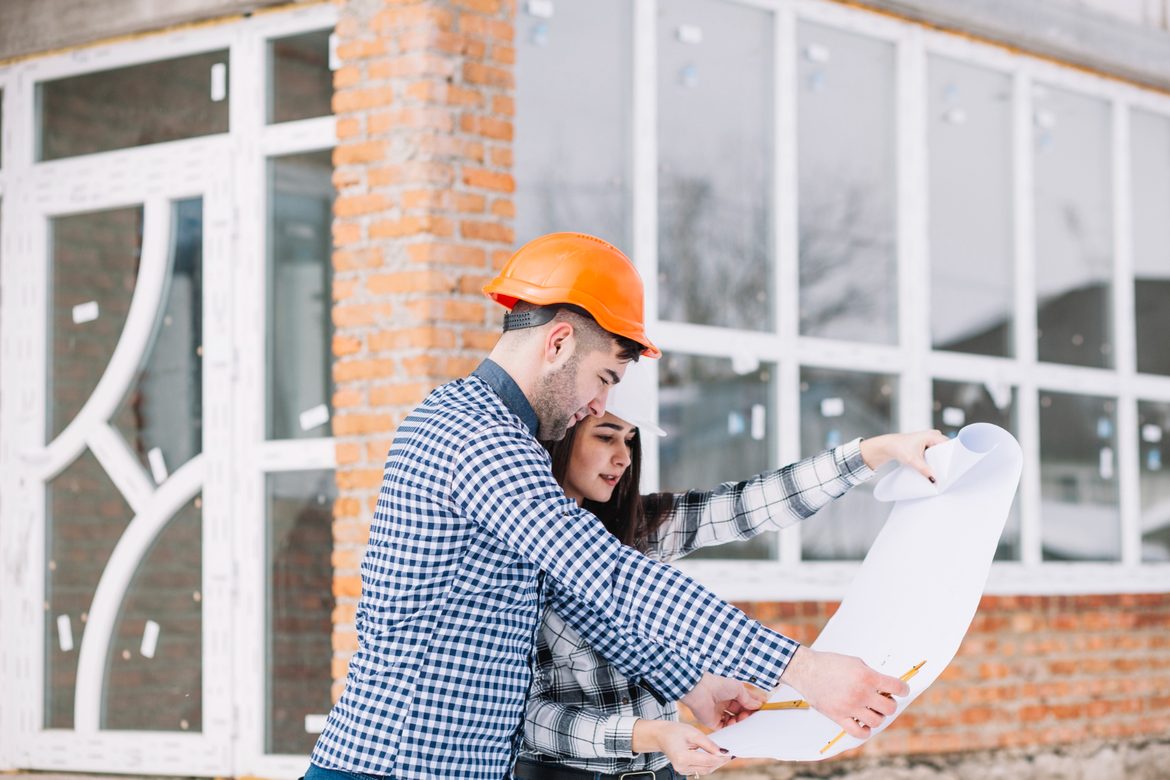 Woman and man looking at a plan in front of a new house.