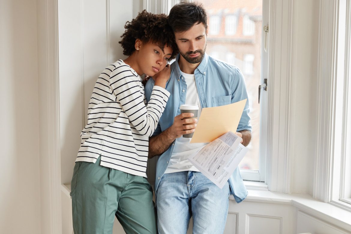 Young couple in a new home looking at paperwork by a window